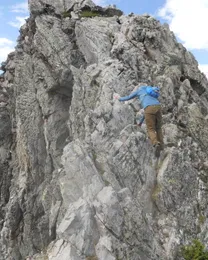 A climber ascending a grey granite buttress on the Quemado Cirque ridge.
