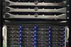 A server rack with three Dell rack servers above a Tripp Lite unit and a storage chassis of hot-swap drive bays lit by blue activity lights.