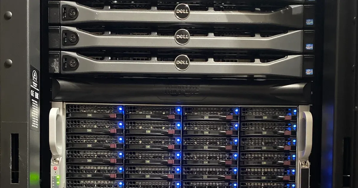 A server rack with three Dell rack servers above a Tripp Lite unit and a storage chassis of hot-swap drive bays lit by blue activity lights.