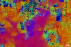 False-color composite of the first three principal components of an 8-band satellite scene, with fields in orange and magenta, a town in green and blue, and a road crossing the upper right.